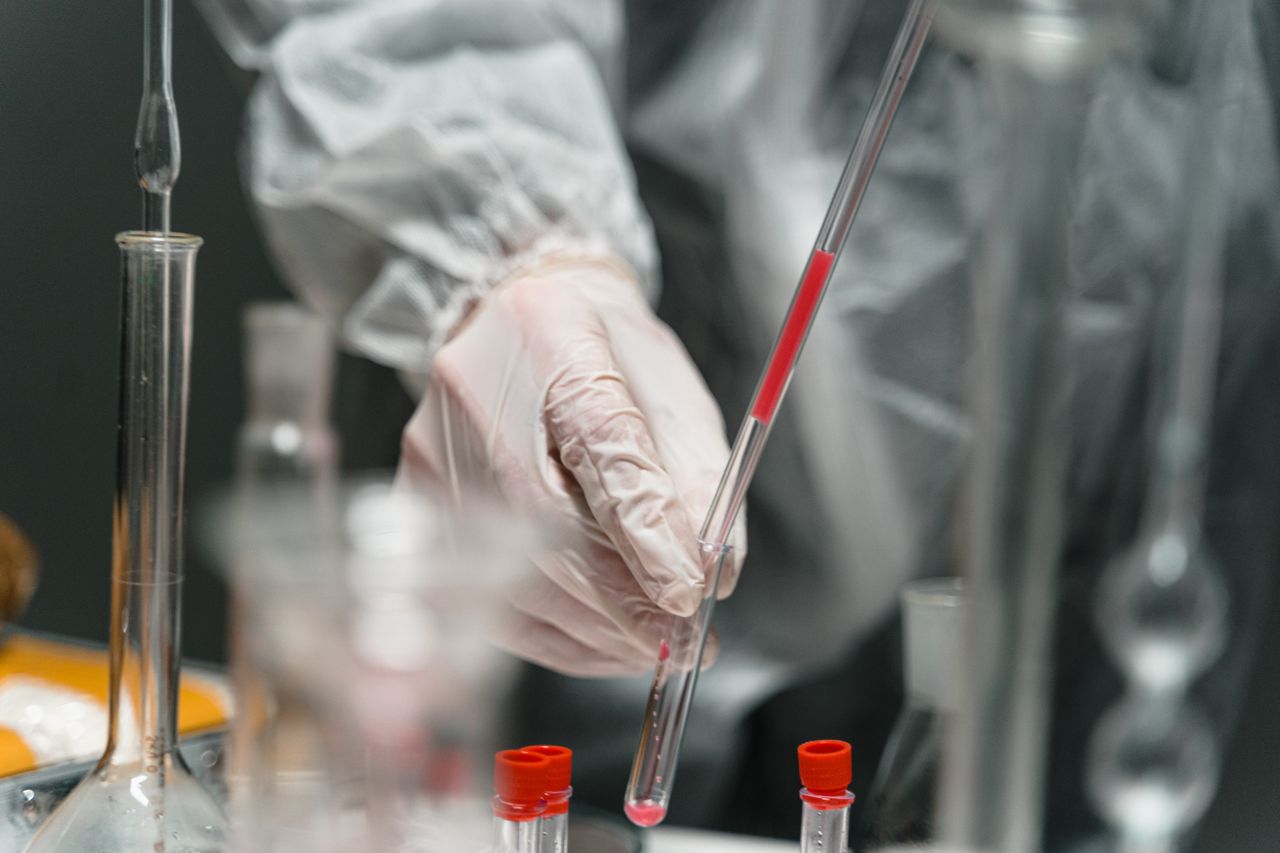 A scientist in gloves working with test tubes in a laboratory environment.